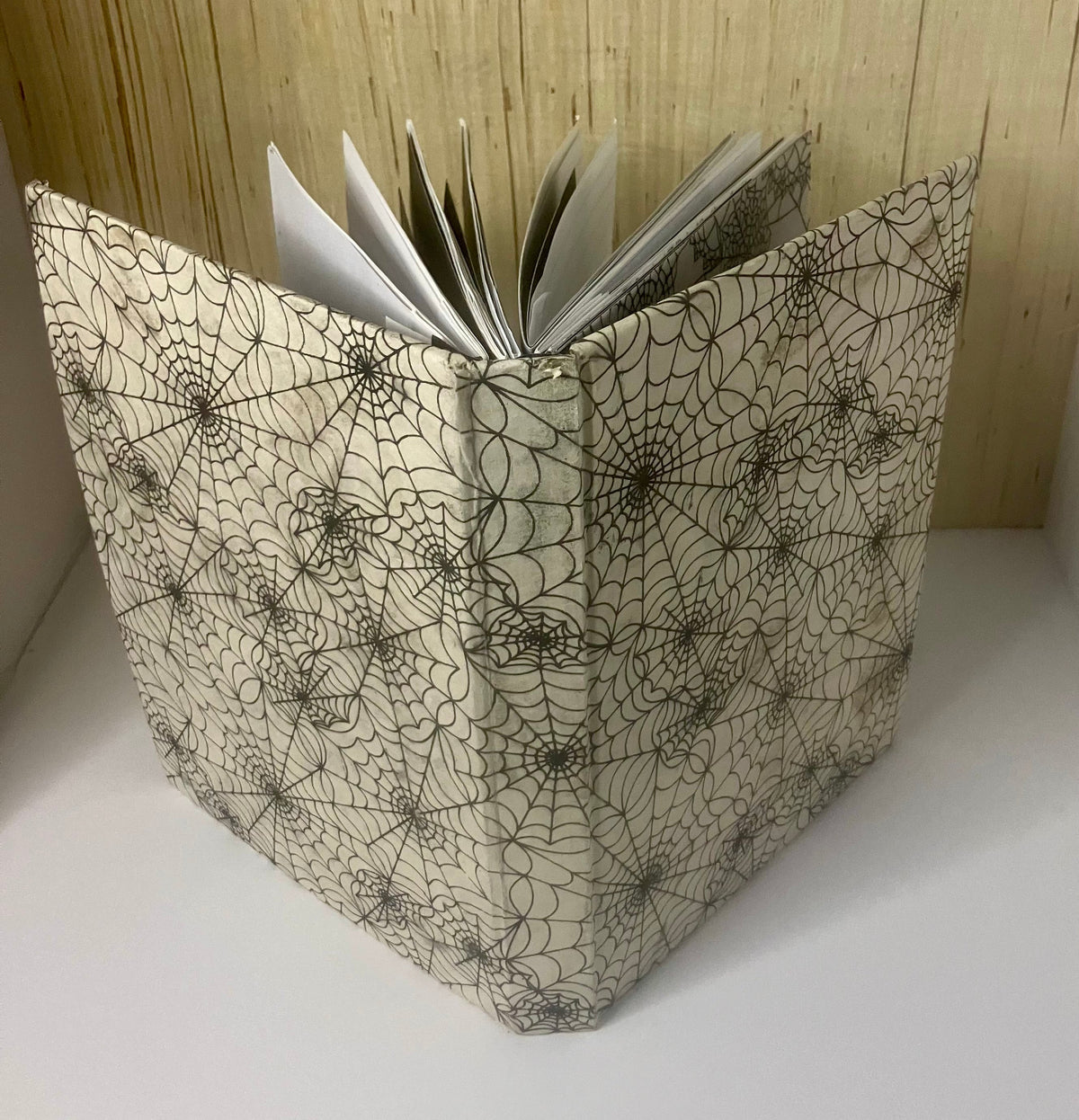 Cream journal cover patterned with black spiderwebs
