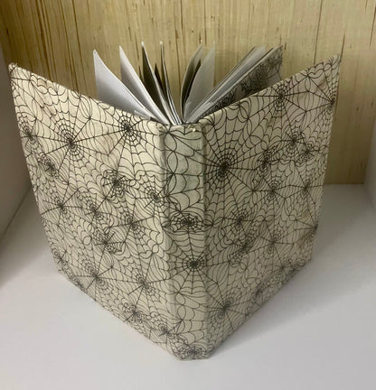 Cream journal cover patterned with black spiderwebs