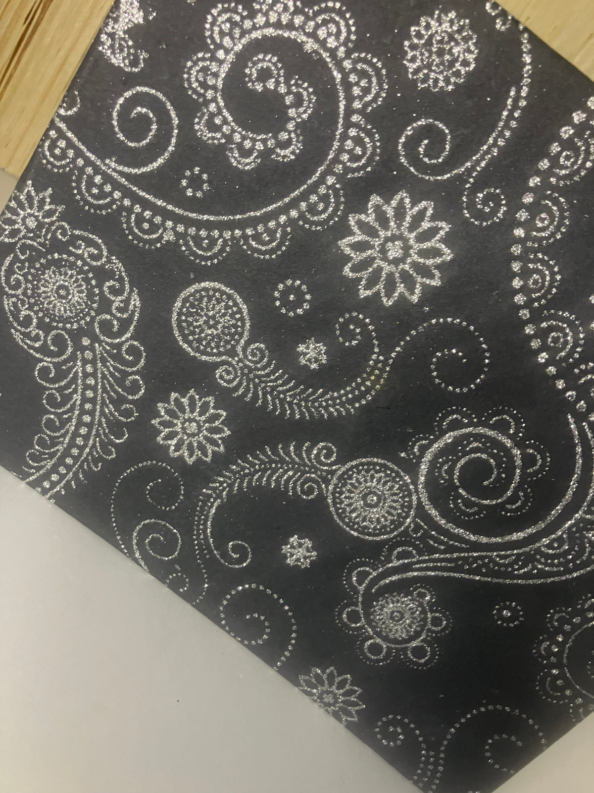 Close-up of glittering floral and paisley motifs on a black journal cover