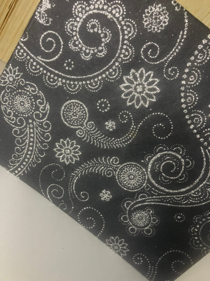 Close-up of glittering floral and paisley motifs on a black journal cover