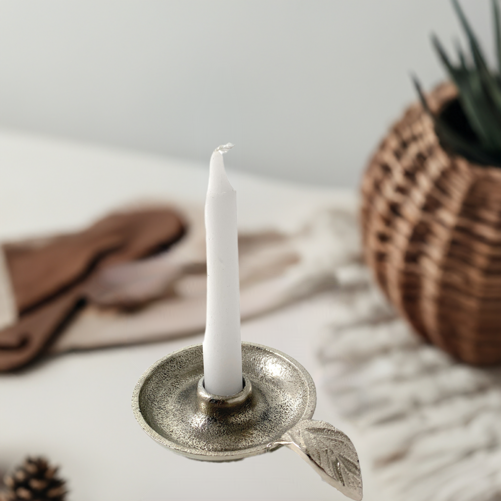 Silver leaf-handle candle holder with a white taper on a neutral table setting