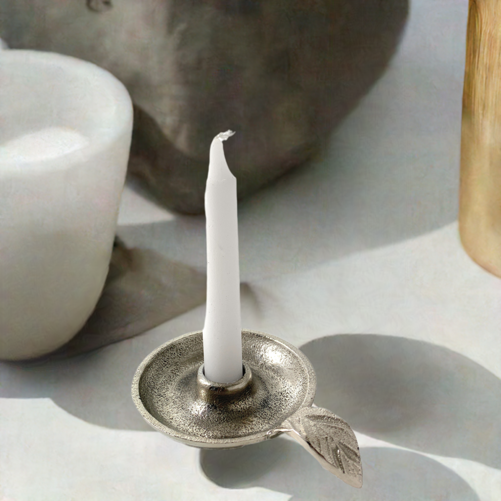 Silver taper candle holder beside neutral decorative bowls