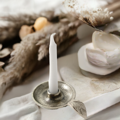 Silver taper candle holder styled with dried flowers and pale ceramics