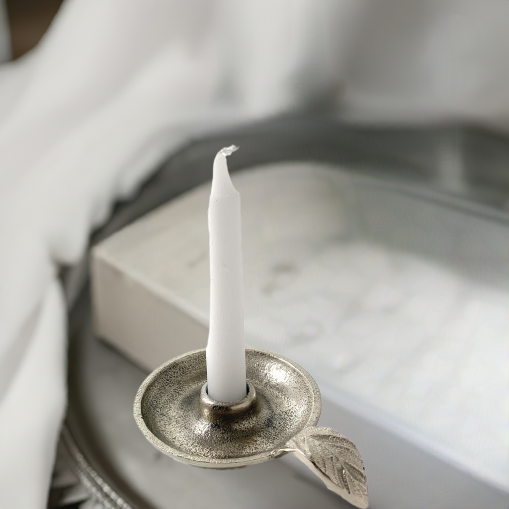 Silver leaf-handle candle holder styled on a pale tray