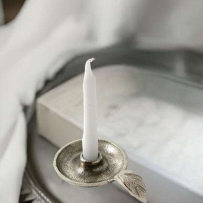 Silver leaf-handle candle holder styled on a pale tray