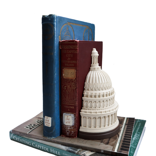 Capitol dome bookend supporting blue and red books on a stack of volumes